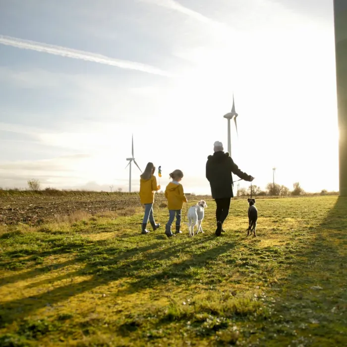 Landschaft mit Personen vor Windrädern